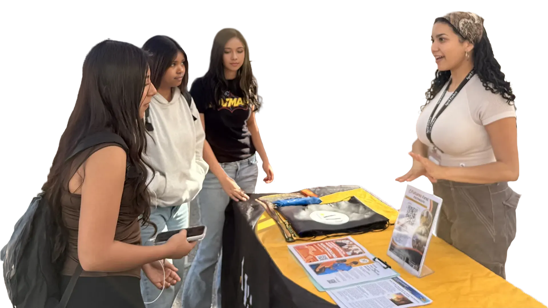 An outreach volunteer talking with three teens at a Futures First info table